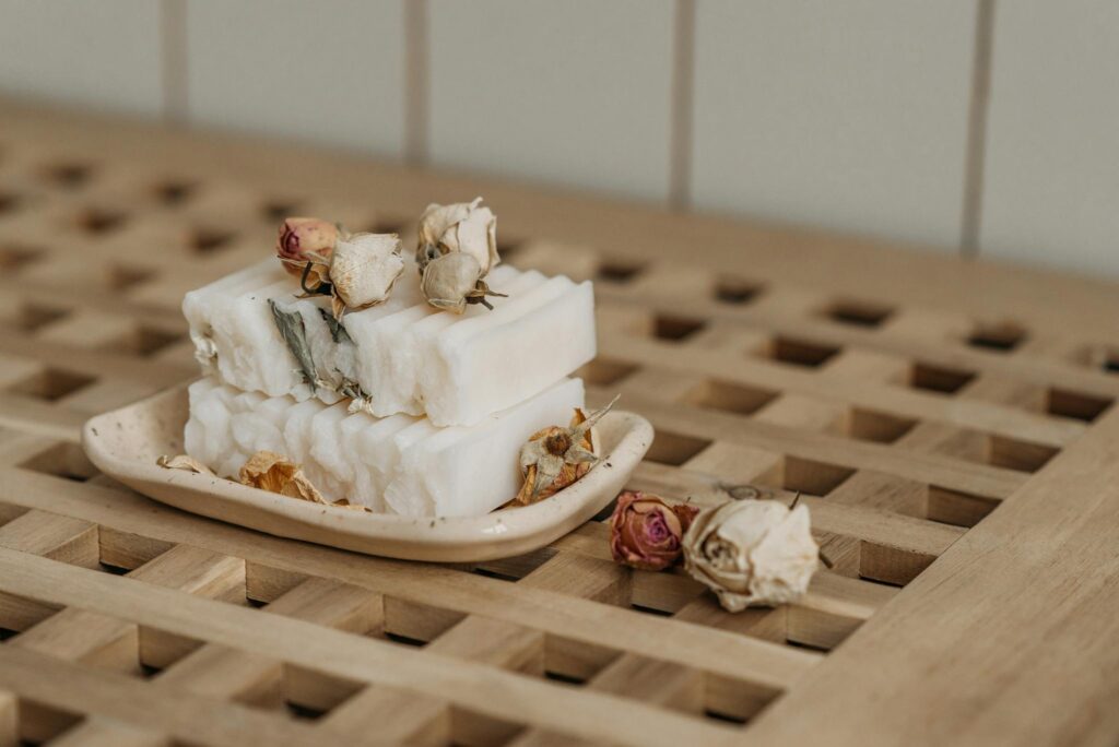 Close-up of natural artisan soaps adorned with dried roses on a ceramic tray, showcasing eco-friendly living.