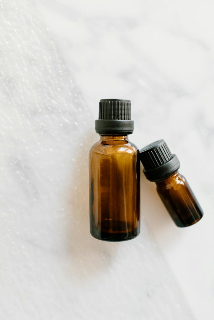 Minimalist brown glass bottles used for essential oils on a white textured surface.